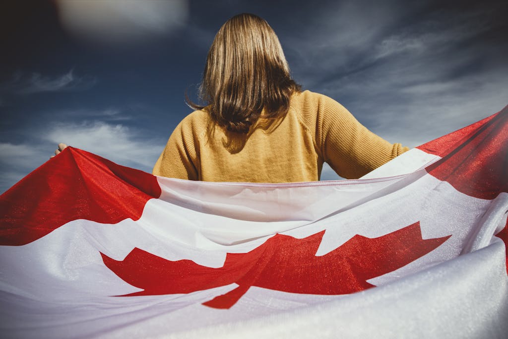 A woman holding the Canadian flag with mountains in Banff, Alberta, Canada.